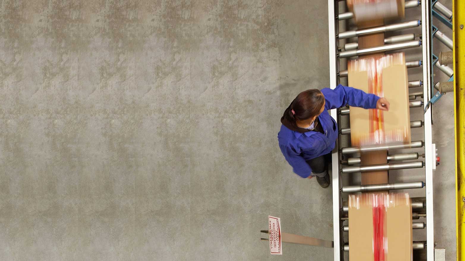 overhead view of a warehouse worker handling a box on a shipping line