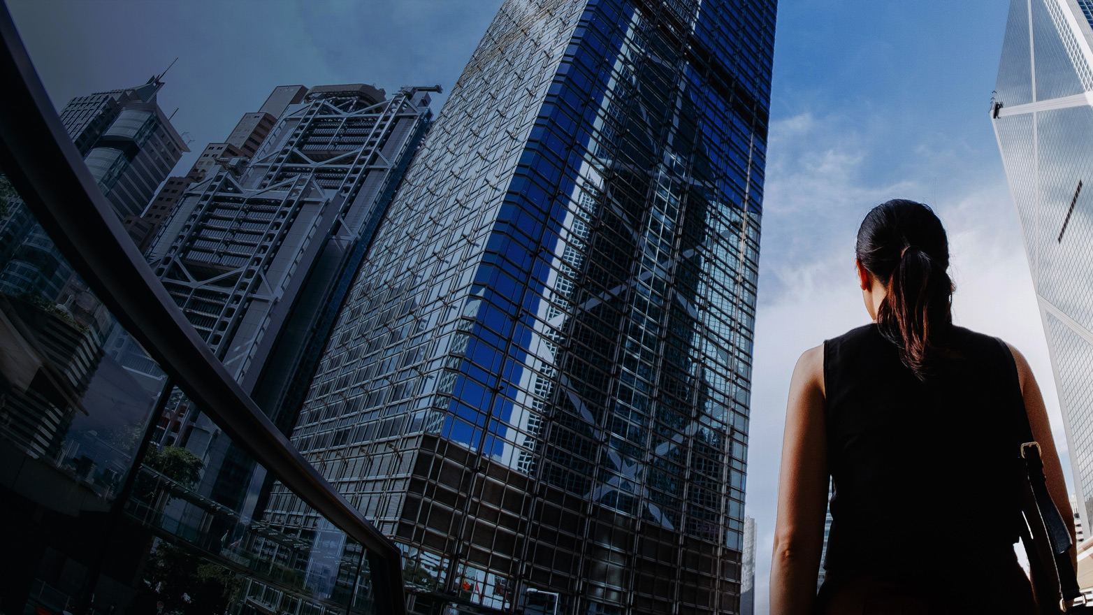 woman standing on street looking up at skyscrapers