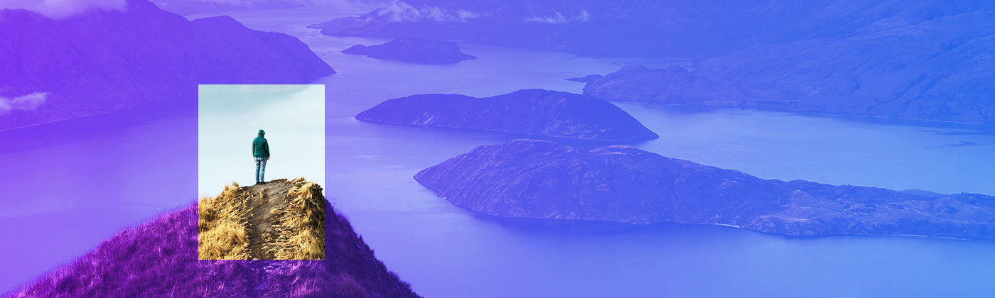 person on mountain peak overlooking large lake