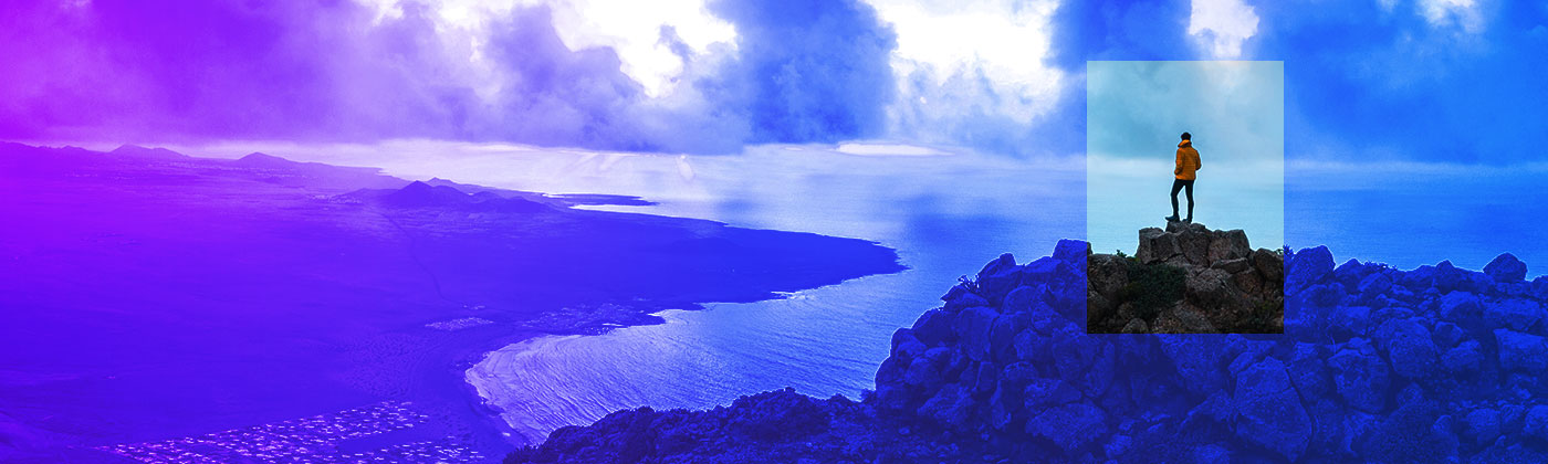 person atop craggy mountain overlooking ocean below