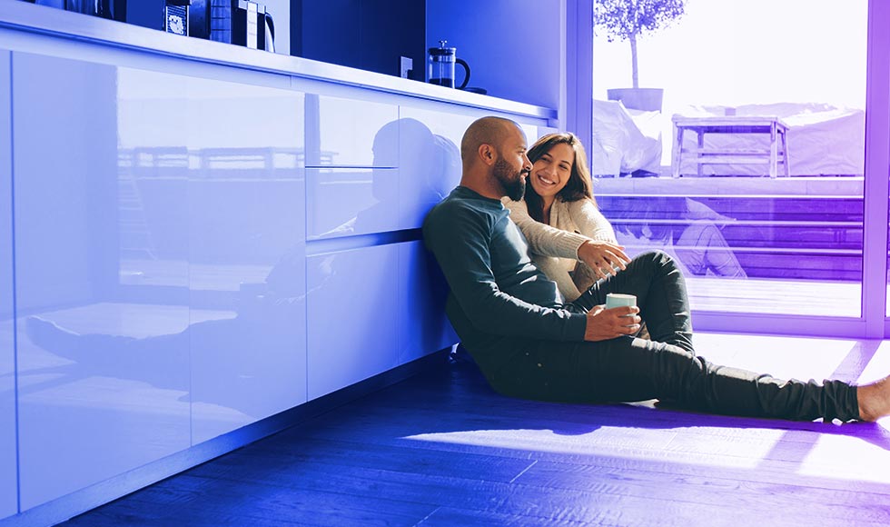 married couple sitting on kitchen floor of new home